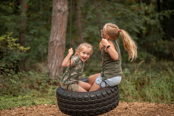 two funny girls swing on a swing