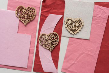 three plain wooden heart shapes on pink and red paper 