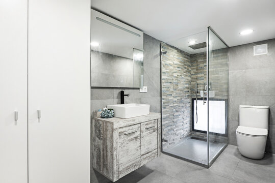 Toilet with white cabinet, porcelain sink and glass pane shower cubicle