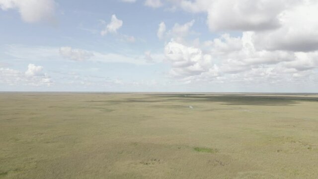 Panoramic pan of everglades savanna to low highway cutting through
