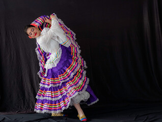 Colombian woman dancing with Tolima Folklore white and purple dress costume with black background and copy space 