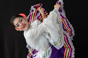 Colombian woman dancing  with Tolima Folklore white and purple dress costume with black background 