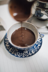 hot chocolate being poured into blue and white Japanese teacup and saucer 