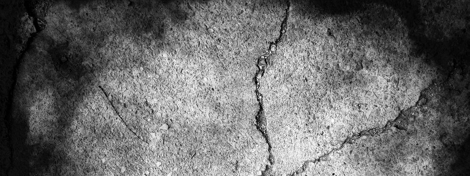 Dark cracked earth with a bright spot for designers, background