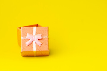 pink gift box with an open lid on a yellow background with copyspace