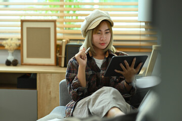 Photo of a young fashion designer using a digital tablet and stylus pen for checking her business...