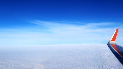 endless clouds under the plane and the blue, bottomless blue sky, the plane makes a maneuver. an airplane wing rises up into the blue sky and descends