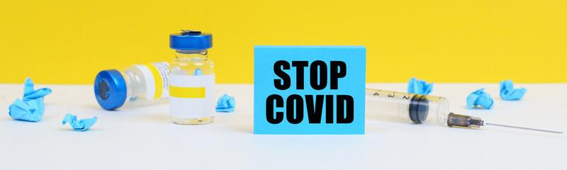 On the table is a syringe, injections and a blue sign with the inscription - STOP COVID