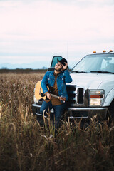 JOVEN MEXICANO CANTANDO CON SU GUITARRA USA SOMBRERO Y TIENE BARBA
