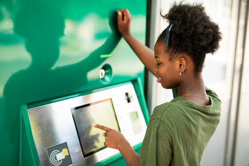 Beautiful African girl using ATM machine. Happy smiling young woman withdrawing money from credit card..