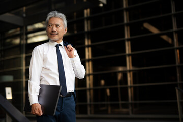 Portrait of senior businessman with laptop. Handsome man in suit outdoors.