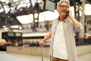 Happy senior man waiting a train. Man talking to the phone while waiting a train.