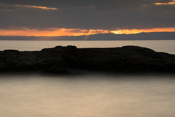 遠くに光芒の見える夕方の海　-長時間露光