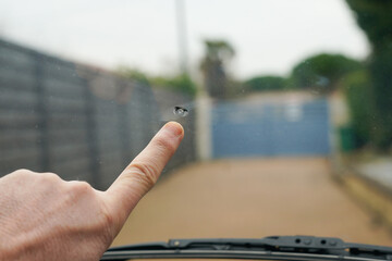 Broken windshield motorcar Smashed windscreen of a car cracked glass pointed watch of finger hand