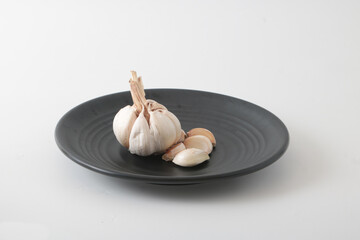 Fototapeta na wymiar A few cloves of garlic on a black plate.