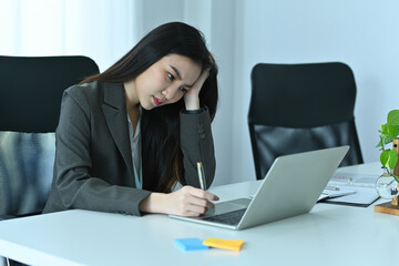 Photo of exhausted office woman sitting in front of a computer laptop at the modern working desk.