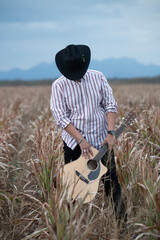 JOVEN MEXICANO CANTANDO CON SU GUITARRA USA SOMBRERO Y TIENE BARBA