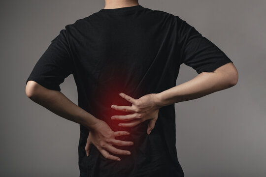 Office syndrome concept back pain , low back pain. young man touches lower back at a pain point.