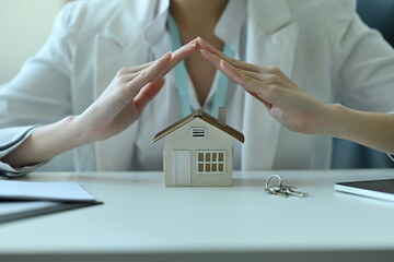Insurance house concept. Closed up with  insurance agent presents the hands protection model that symbolize the coverage.
