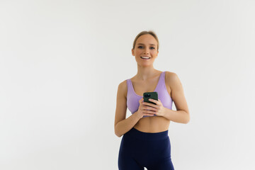 Two fitness young women using smartphone while resting after working out in a gym.