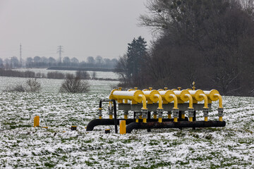 Yellow gas infrastructure elements sticking out of the ground. Winter photo of a snow-covered gas...