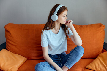 woman sitting on the couch at home listening to music on headphones apartments