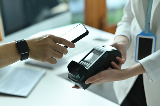 Cropped image of customer's hand holding a smartphone for doing a payment by using NFC technology.