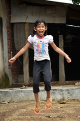 A cute girl child or kid is jumping with laughing and smiling  funny face selective focus blur background portrait