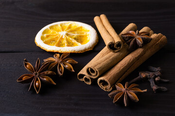 Dried orange slice, cinnamon sticks and anise on dark wooden background. Traditional christmas composition