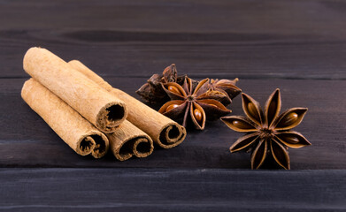Spice cinnamon sticks and anise on dark wooden background.