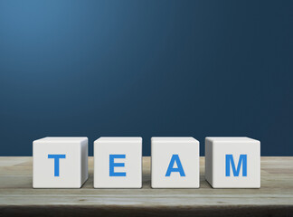 TEAM letter on white block cubes on wooden table over light blue gradient background, Business teamwork communication concept