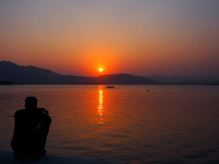 Naklejka na ściany i meble Sunset at a lake pichola in Udaipur, India.