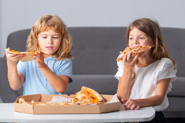 Children eating pizza. Little children friends, boy and girl bite pizza.