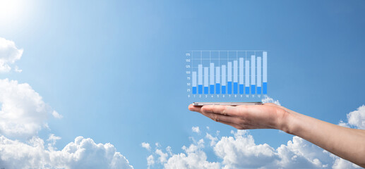 Business man holding tablet and showing holographic graphs and stock market statistics gain profits. Concept of growth planning and business strategy. Display of good economy form digital screen.