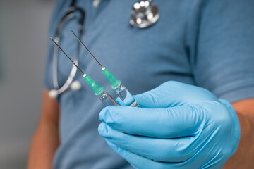 close up of doctor's hand handling two pulled up syringes with coronavirus vaccine
