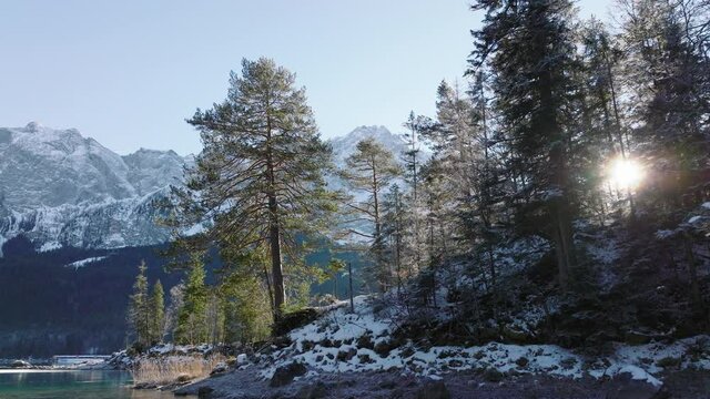 Eibsee Lake in Bavaria at the foot of Zugspitze in Winter - Low wide shot moving up, forward and panning down - Aerial 4k