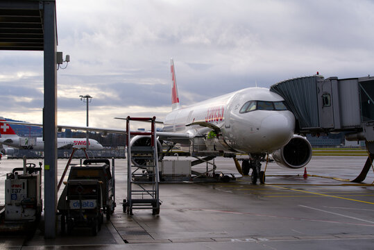 Parked Swiss airplane Airbus A321 register HB-JPB with airport worker at Terminal A of Zürich Airport on a rainy winter day. Photo taken December 26th, 2021, Zurich, Switzerland.