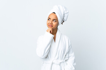 Young woman in bathrobe over isolated white background having doubts