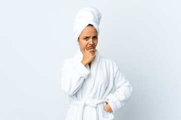 Young woman in bathrobe over isolated white background having doubts