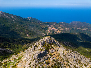 Fototapeta na wymiar Panorama aerial drone landscape of Monte Capanne, highest moutain on Elba with green landscape and mediterranean sea in the backgroud 
