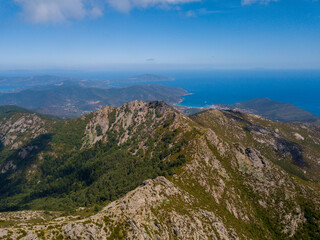 Naklejka na ściany i meble Panorama aerial drone landscape of Monte Capanne, highest moutain on Elba with green landscape and mediterranean sea in the backgroud 