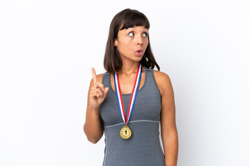 Young mixed race woman with medals isolated on white background thinking an idea pointing the finger up