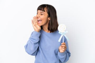 Young mixed race woman holding a lollipop isolated on white background shouting with mouth wide open to the side