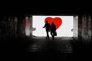 Silhouette of a man in a dark tonel against a background of a large red heart. Love, loneliness, conceptual photo. 