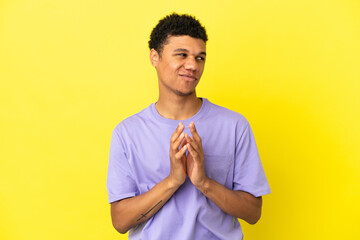 Young African American man isolated on yellow background scheming something