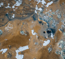 Aerial Drone panorama with hot steam coming from the ground. Hverir is geothermal area in Myvatn. Landscape covered with snow and orange ground.