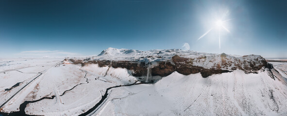 Aerial drone photo of Seljalandsfoss waterfall in Iceland captured in winter. Top view of Nordic majestic waterfall with tourists from above. Winter beauty landscape with frozen water