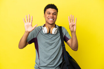 Young sport African American man with sport bag isolated on yellow background counting nine with...