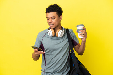 Young sport African American man with sport bag isolated on yellow background holding coffee to...