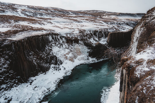 Aerial Drone view of Fjadrargljufur canyon and Fjadra river at winter. White snow and blue river. Iceland near Reykjavik.